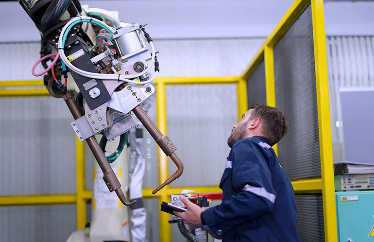 An EY engineer checking a robot at a workshop.